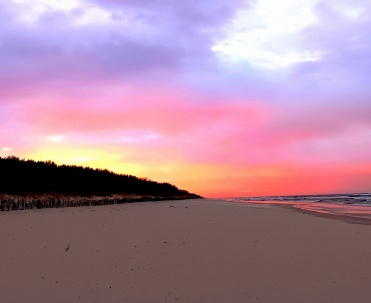 Intensywnie r&oacute;żowe niebo nad pustą plażą nadaje Bałtykowi baśniowy wygląd. Ten barwny zach&oacute;d słońca pokazuje wyjątkową atmosferę wieczor&oacute;w w Jastarni.